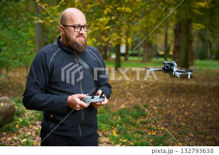 A man controls a small drone in a serene park filled with vibrant autumn leaves. The moment captures the joy of technology blending with nature's beauty. A man controls a small drone in a serene park filled with vibrant autumn leaves. The moment captures the joy of technology blending with nature's beauty. 132793638