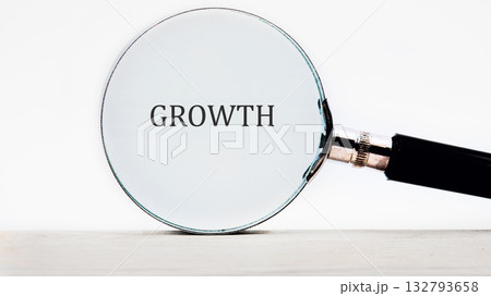A magnifying glass enlarges the word GROWTH, highlighting the concept of progress, development, and enhancement. The background is a simple, clean white A magnifying glass enlarges the word GROWTH, highlighting the concept of progress, development, and enhancement. The background is a simple, clean white 132793658