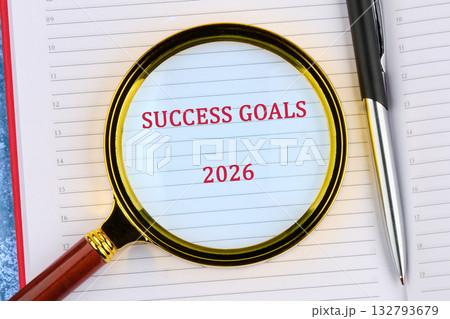 A close-up shows Success Goals and 2026 written in red on a notepad page, being viewed through a magnifying glass. A pen is placed next to the glass A close-up shows Success Goals and 2026 written in red on a notepad page, being viewed through a magnifying glass. A pen is placed next to the glass 132793679