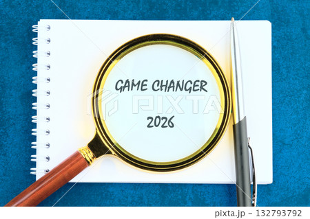 A clear notepad with the phrase Game Changer 2026 written boldly, accompanied by a magnifying glass and a sleek pen. This setup inspires creativity and future planning 132793792