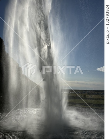 アイスランドの南部の滝、セリャラントスフォスの滝壺の裏から見た滝と直瀑の先に見える輝く太陽です。 アイスランドの南部の滝、セリャラントスフォスの滝壺の裏から見た滝と直瀑の先に見える輝く太陽です。 132793924