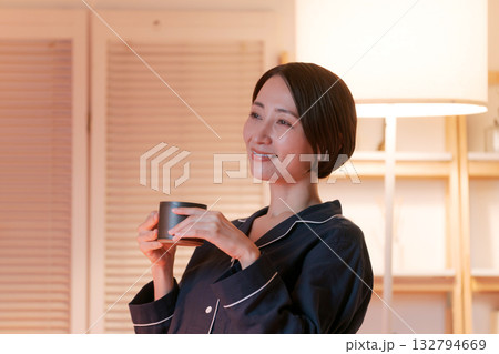 夜、部屋でホットドリンクを飲むパジャマの女性 夜、部屋でホットドリンクを飲むパジャマの女性 132794669