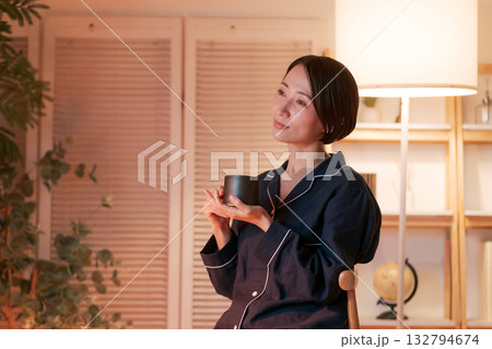 夜、部屋でホットドリンクを飲むパジャマの女性 夜、部屋でホットドリンクを飲むパジャマの女性 132794674
