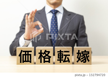 「価格転嫁」と書かれたブロックとOKポーズをするビジネスマン 「価格転嫁」と書かれたブロックとOKポーズをするビジネスマン 132794720