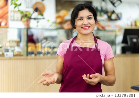 Polite waitress welcomes clients in cafeteria Polite waitress welcomes clients in cafeteria 132795881