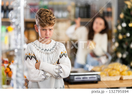 Sad boy while shopping with mother at grocery store on New Years Eve. Sad boy while shopping with mother at grocery store on New Years Eve. 132795894
