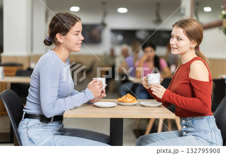 Girl in cafe sits near girl companion; has nice conversation and discusses news of day Girl in cafe sits near girl companion; has nice conversation and discusses news of day 132795908
