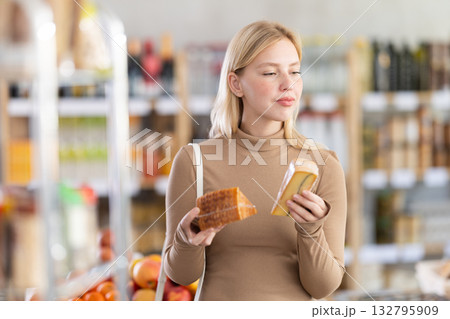 Girl buyers examine good, doubt and choose cheese in store 132795909