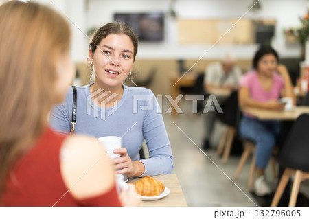 Young woman and her friend drinking coffee and talking Young woman and her friend drinking coffee and talking 132796005
