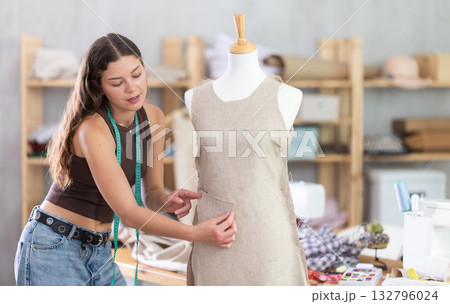 Female fashion designer sewing dress and testing it on mannequin Female fashion designer sewing dress and testing it on mannequin 132796024