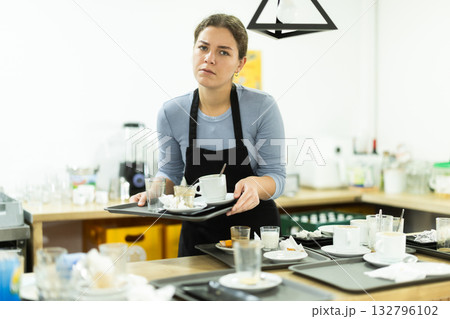 Cafe waitress carries a tray with dirty dishes closeup 132796102