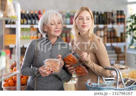 Girl and grandmother buyers examine good, doubt and choose prawn in store Girl and grandmother buyers examine good, doubt and choose prawn in store 132796167