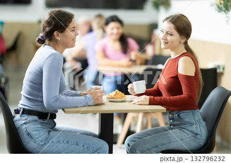 Two young women drinking coffee with croissant Two young women drinking coffee with croissant 132796232