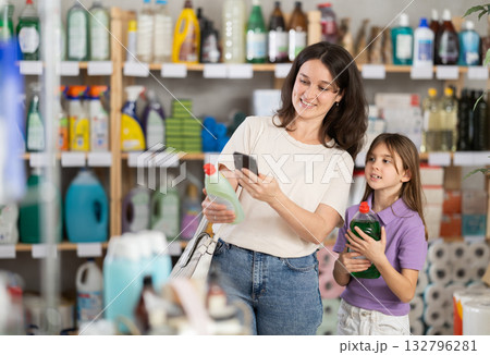 Mother and daughter checking expiration date of dishwashing liquid using smartphone in household supermarket Mother and daughter checking expiration date of dishwashing liquid using smartphone in household supermarket 132796281