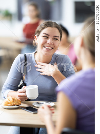 Young woman and her friend drinking coffee and talking Young woman and her friend drinking coffee and talking 132796330