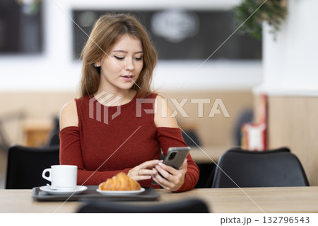 Young woman with phone in cafe Young woman with phone in cafe 132796543
