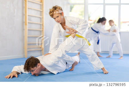 Judo or jiu jitsu classes - family with two children practicing grabbing and throwing on sports mats Judo or jiu jitsu classes - family with two children practicing grabbing and throwing on sports mats 132796595