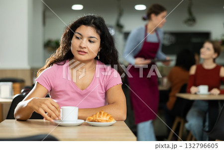 Attractive female sitting alone at table in cozy cafe, drinking fragrant coffee Attractive female sitting alone at table in cozy cafe, drinking fragrant coffee 132796605