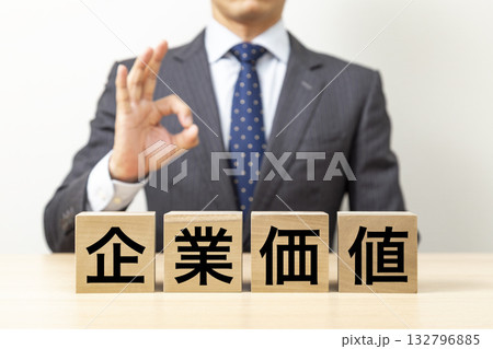 「企業価値」と書かれたブロックとOKポーズをするビジネスマン 「企業価値」と書かれたブロックとOKポーズをするビジネスマン 132796885