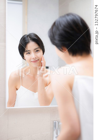 洗面台で鏡を見ながらスキンケアする女性 洗面台で鏡を見ながらスキンケアする女性 132797674