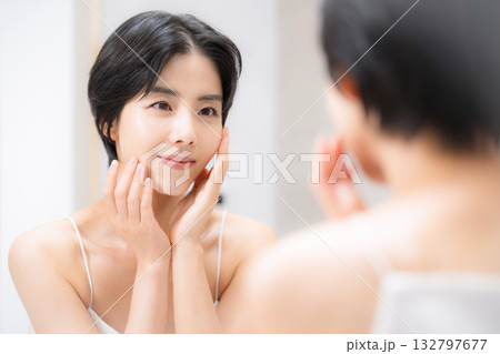 洗面台で鏡を見ながらスキンケアする女性 132797677