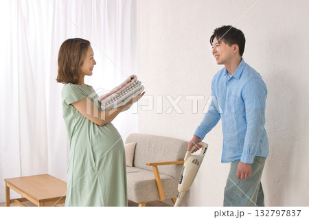 妊婦の女性と楽しそうに話しながら掃除機をかける若い男性 132797837