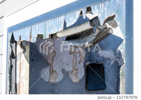 Damage to exterior wall reveals insulation and pipes after fire incident in residential building during daylight hours 132797976