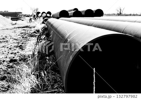 Metal pipes lined up on the ground in a construction site during a clear daylight in an industrial area Metal pipes lined up on the ground in a construction site during a clear daylight in an industrial area 132797982