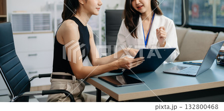 Businesswomen work and discuss their business plans. A Human employee explains and shows her colleague the results paper Businesswomen work and discuss their business plans. A Human employee explains and shows her colleague the results paper 132800468