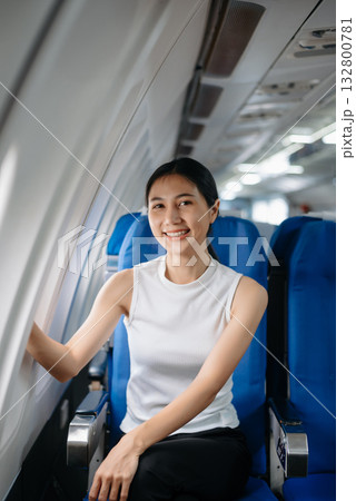 Attractive Asian female passenger of airplane sitting in comfortable seat while working laptop and tablet. Travel in style, work with grace. 132800781