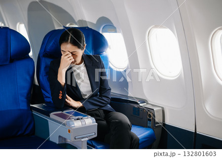 frustrated woman sitting on an airplane with her head in her hands. Asian woman sitting in a seat in airplane 132801603
