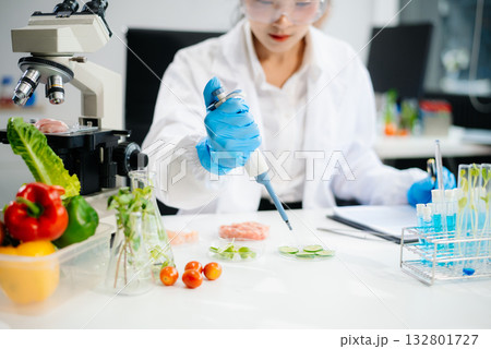 Two Asian scientists in a lab conducting food research using a microscope and lab equipment, showcasing innovation in food science 132801727
