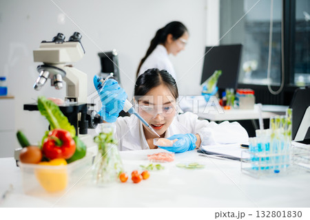 Two Asian scientists in a lab conducting food research using a microscope and lab equipment, showcasing innovation in food science 132801830