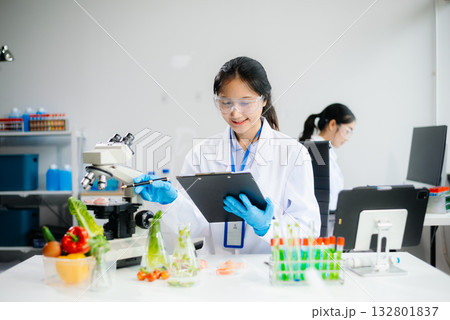 Two Asian scientists in a lab conducting food research using a microscope and lab equipment, showcasing innovation in food science 132801837
