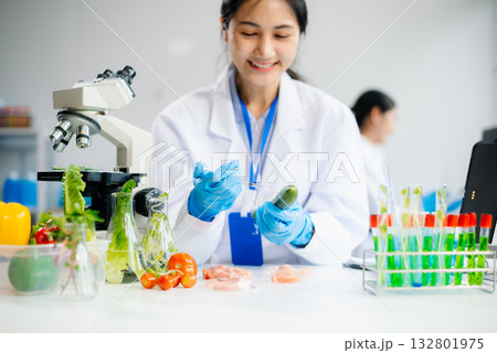 Two Asian scientists in a lab conducting food research using a microscope and lab equipment, showcasing innovation in food science 132801975