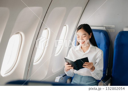 Attractive Asian female passenger of airplane sitting in comfortable seat while working laptop and tablet with mock up area using wireless connection. Attractive Asian female passenger of airplane sitting in comfortable seat while working laptop and tablet with mock up area using wireless connection. 132802054