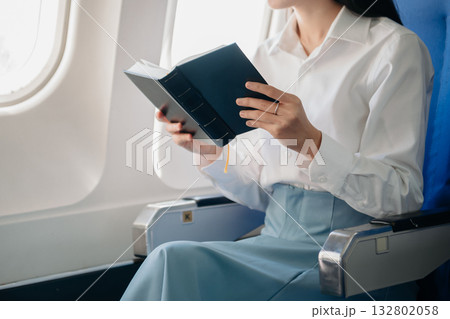 Young Asian executive excels in first class, multitasking with digital tablet, laptop and smartphone. Travel in style, work 132802058