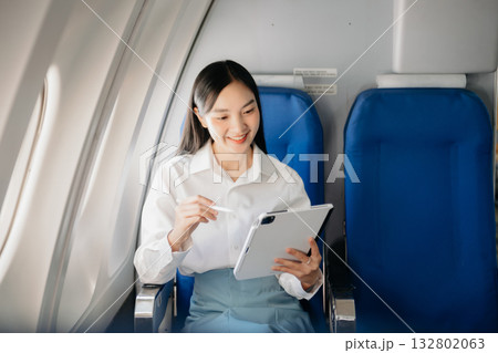Young Asian executive excels in first class, multitasking with digital tablet, laptop and smartphone. Travel in style, work Young Asian executive excels in first class, multitasking with digital tablet, laptop and smartphone. Travel in style, work 132802063
