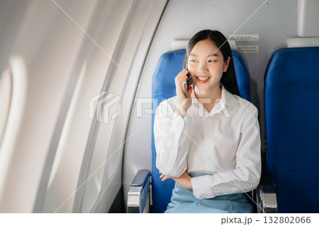 Attractive Asian female passenger of airplane sitting in comfortable seat while working laptop and tablet with mock up area using wireless connection. Attractive Asian female passenger of airplane sitting in comfortable seat while working laptop and tablet with mock up area using wireless connection. 132802066