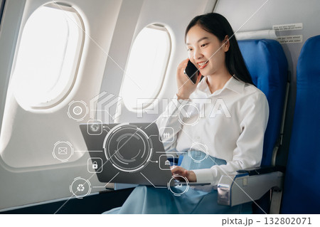 Attractive Asian female passenger of airplane sitting in comfortable seat while working laptop and tablet with mock up area using wireless connection. Attractive Asian female passenger of airplane sitting in comfortable seat while working laptop and tablet with mock up area using wireless connection. 132802071