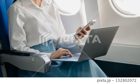 Attractive Asian female passenger of airplane sitting in comfortable seat while working laptop and tablet with mock up area using wireless connection. Attractive Asian female passenger of airplane sitting in comfortable seat while working laptop and tablet with mock up area using wireless connection. 132802072