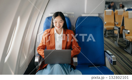 Attractive Asian female passenger of airplane sitting in comfortable seat while working laptop and tablet with mock up area using wireless connection. Attractive Asian female passenger of airplane sitting in comfortable seat while working laptop and tablet with mock up area using wireless connection. 132802101