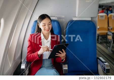 Young Asian executive excels in first class, multitasking with digital tablet, laptop and smartphone. Travel in style, work 132802179