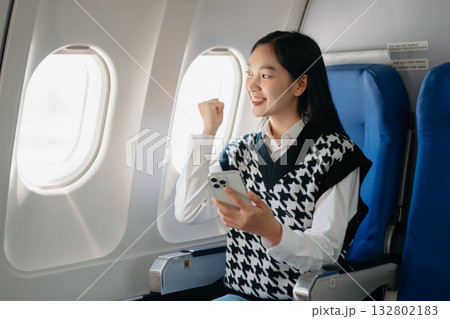 Attractive Asian female passenger of airplane sitting in comfortable seat while working laptop and tablet with mock up area using wireless connection. Attractive Asian female passenger of airplane sitting in comfortable seat while working laptop and tablet with mock up area using wireless connection. 132802183