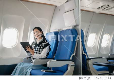 Young Asian executive excels in first class, multitasking with digital tablet, laptop and smartphone. Travel in style, work Young Asian executive excels in first class, multitasking with digital tablet, laptop and smartphone. Travel in style, work 132802213