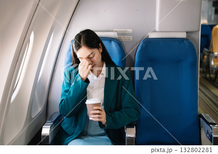 Photo of a frustrated woman sitting on an airplane with her head in her hands. Asian woman sitting in a seat Photo of a frustrated woman sitting on an airplane with her head in her hands. Asian woman sitting in a seat 132802281