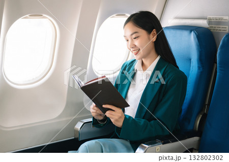 Attractive Asian female passenger of airplane sitting in comfortable seat while working laptop and tablet with mock up area using wireless connection. Attractive Asian female passenger of airplane sitting in comfortable seat while working laptop and tablet with mock up area using wireless connection. 132802302