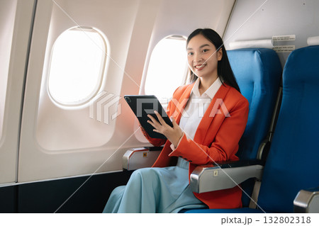 Attractive Asian female passenger of airplane sitting in comfortable seat while working laptop and tablet with mock up area using wireless connection. Attractive Asian female passenger of airplane sitting in comfortable seat while working laptop and tablet with mock up area using wireless connection. 132802318