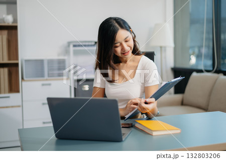 Young beautiful woman typing on tablet and laptop while sitting at the working white table Young beautiful woman typing on tablet and laptop while sitting at the working white table 132803206