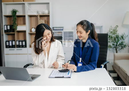 Female discussing new project with Female colleague. Young women talking with young Asian man in office. 132803318